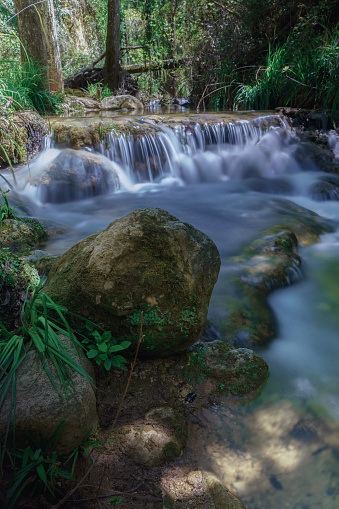 long exposure silk effect photograph of a waterfall in a mountain stream with lush vegetation