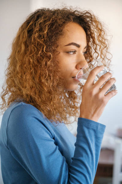istock young woman drinking water at home 2145063675
