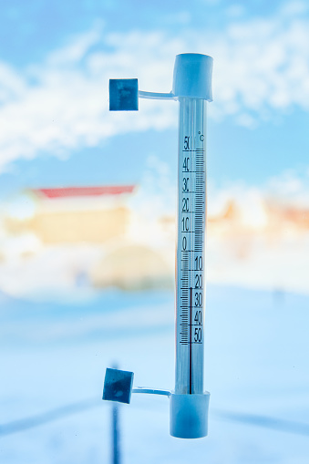 Low air temperature is indicated by an outdoor thermometer with scale in degrees Celsius, fixed to outside of window glass with adhesive tape.
