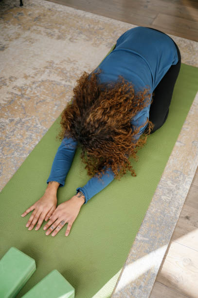 istock woman in child pose, practicing yoga at home 2145064726