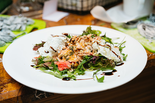 Delicious grilled chicken salad served with mixed greens and a creamy dressing on a white plate.