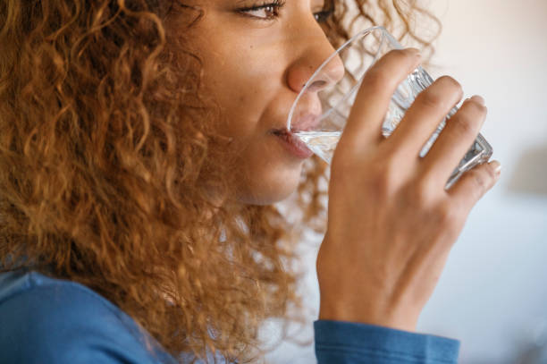 istock young woman drinking water at home 2145070477