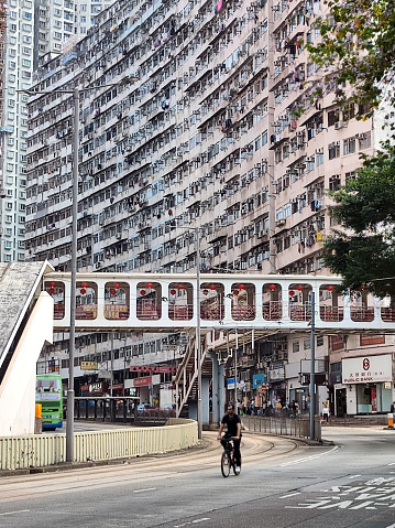 Cyclist on King's road by the enormous Yick Cheong residential building (also called the Monster building) in Quarry Bay, Hong Kong island.
