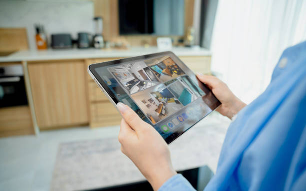 istock Young woman looking at home security cameras on tablet computer 2145101123