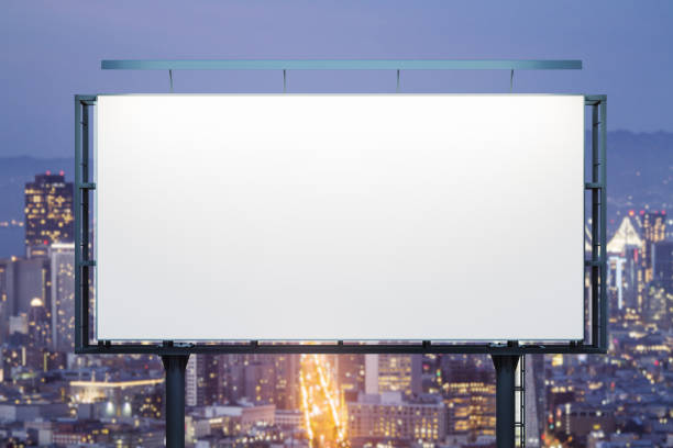 istock Blank white horizontal billboard on city buildings background at night, front view. Mockup, advertising concept 2145105815