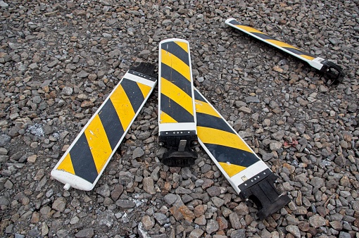 4 yellow and black caution signs lying on the gravel