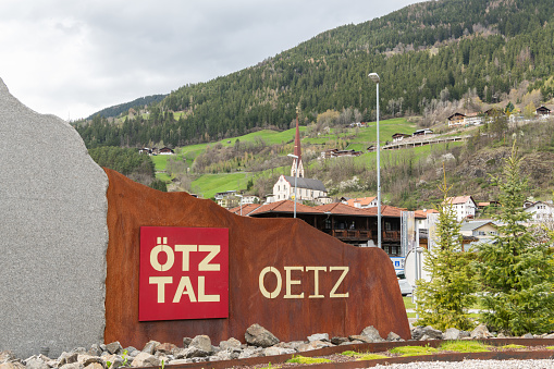 Sign of the village Oetz in The ötztal valley in Tyrol with the church and mountains in the background. Early spring view. Tourist-spot, mmust-see village in Austria. 4 april 2024, Oetz, Austria.