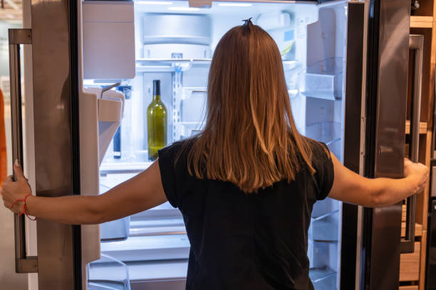 istock Contemporary Kitchen Scene with Woman Opening a Large, Well-Stocked Refrigerator 2145143579