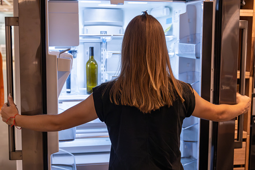 Contemporary Kitchen Scene with Woman Opening a Large, Well-Stocked Refrigerator