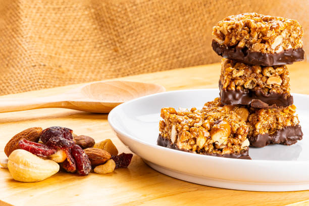 istock Stack of peanuts, almond and chocolate mini protein bars in white ceramic dish. 2145151981