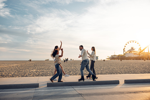 Small group of friends meet by the beach to roller skate together in Santa Monica - Los Angeles, USA