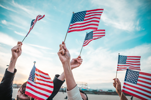 A group of people holding small flags of the USA in their hands