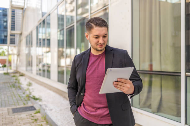 istock Happy and confident businessman using tablet outside the urban office building. 2145245310