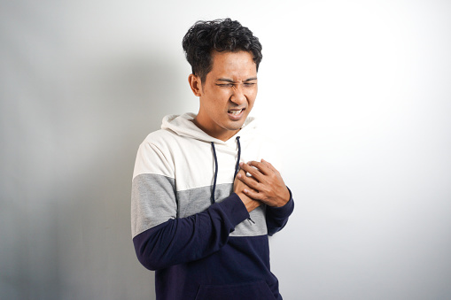 Portrait of Asian man placing hands on the chest suffering from pain in the heart.