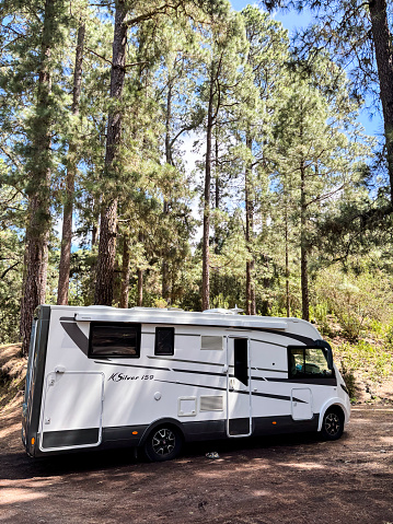 One modern motorhome camper van parking in the nature alone for alternative freedom travel vacation. Living off grid in vanlife style.Recreational vehicle in the woods forest