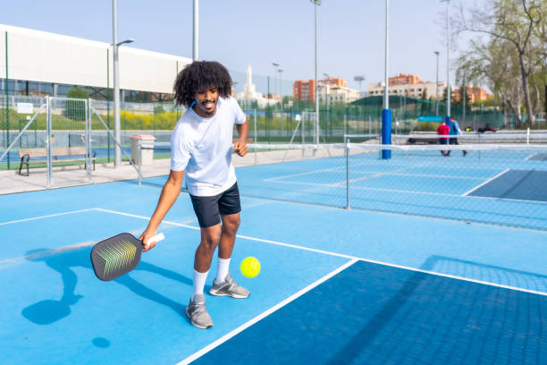 istock Smiling man with afro hair serving while playing pickleball 2145254904