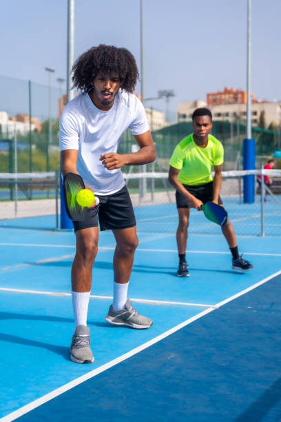 African sportive man serving ball during pickleball match