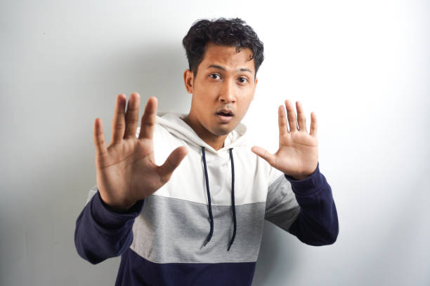 istock Attractive young man makes frightened gesture with palms, defends himself from someone, asks to stop it immediately. Guy says stay away from me, shows stop sign. Body language concept 2145288305