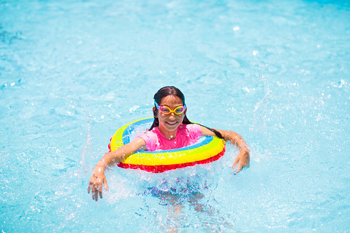 Smiling children wearing snorkel goggles and floating on a yellow raft.