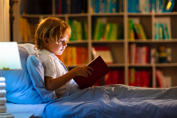 istock Child reading book in bed. Kids read at night. 2145378350