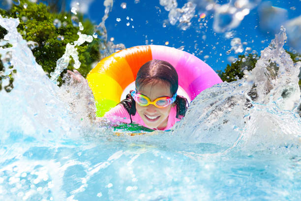 Child in swimming pool on toy ring. Kids swim. Child in swimming pool floating on toy ring. Kids swim. Colorful rainbow float for young kids. Little girl having fun on family summer vacation in tropical resort. Beach and water toys. Sun protection. game resort pictures stock pictures, royalty-free photos & images