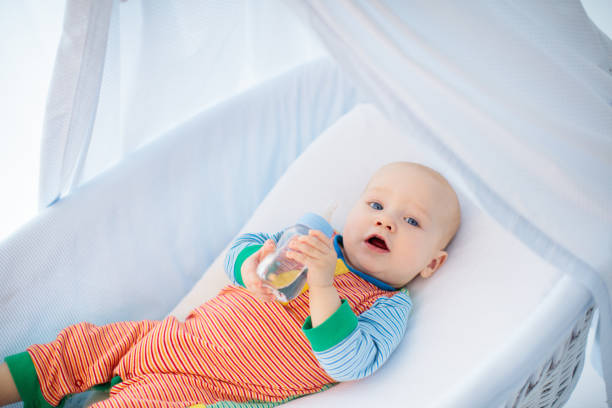 istock Little baby with bottle in white bed 2145418636