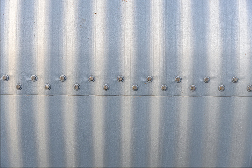 Close up of a corrugated steel plate with bolts and nuts