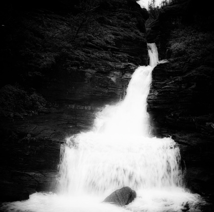 Waterfall in mysterious forest photographed with long exposure to get a tranquil dreamy image, black and white processed