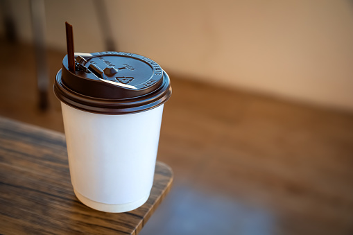 A Paper Cup of Hot Coffee with Plastic Cap Placed on the Table