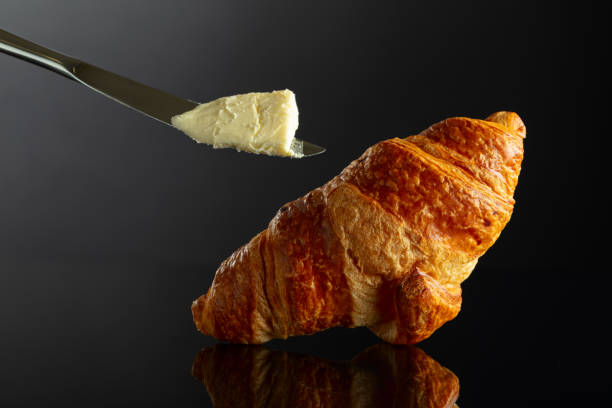 istock Fresh baked croissant with butter on a black background. 2145464535