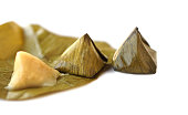 Sweet stuffed dough pyramid or Khanom Tian in Thai language, wrapped by banana leaf and streamed. White background. Concept.  Thai traditional dessert.  Prepare food for cultural celebration events.