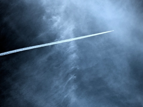 Passenger plane flies on trail on threatening dark sky