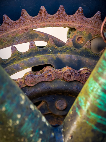 A close-up reveals the deteriorated state of the front chainrings and rusty bicycle chain, contrasted against the worn and shabby frame, indicating urgent need for replacement due to extensive wear.