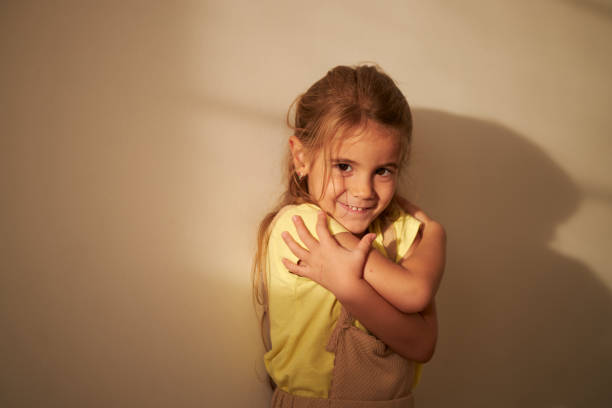 Smiling loving young girl hugging oneself.