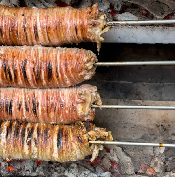 Photo of Grilling Kokorec kebab on skewers, front view.