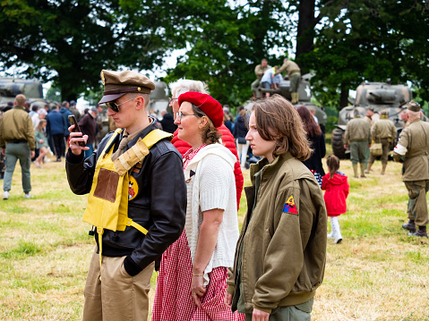 Sainte Mere l'Eglise, Normandy, France - June 6, 2023. Second world war commemoration. Military camp reconstitution. Unidentified vintage dressed family walking during 1944 year