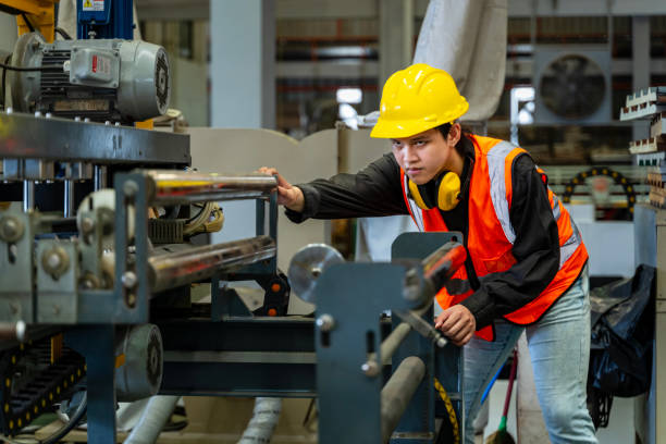 istock Asian industrial worker is checking setup value of metal sheet roll forming machine inside roof factory for safety industry construction 2145591773