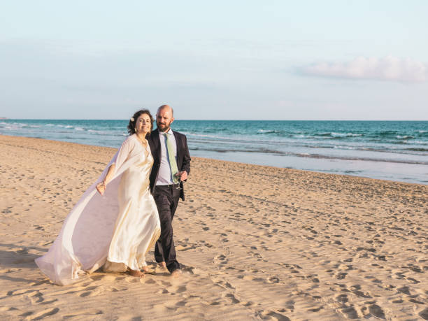 istock Couple Walking Hand in Hand on Beach at Sunset 2145617926