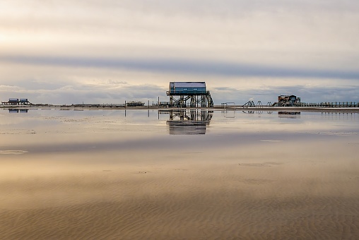 the pile dwellings by Peter Ording with reflection at low tide of the North Sea