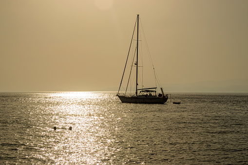 Small boats and yachts at sunset docked on the marina park with oceanfront view in Greece.