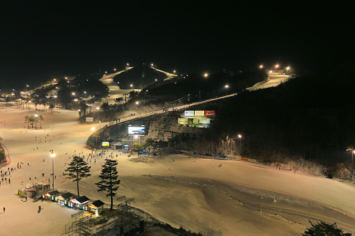 Ski resort at night, you can see people skiing.