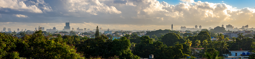 Sun rises over Havana, Cuba, wide-angle panoramic view captures the city's iconic skyline illuminated by the morning sun, creating a stunning vista with misty haze adding to the allure of the scene.