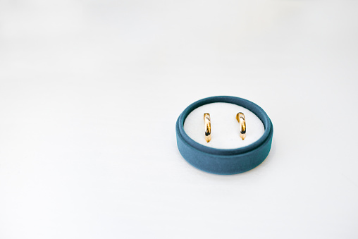 Gold wedding rings in a blue velvet box on a white background with a copy space