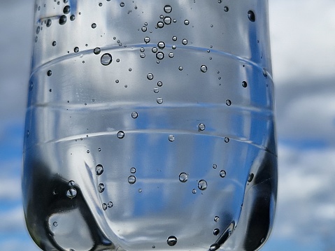 Close-up of an orange slice in liquid with bubbles. Slice of orange fruit in water. Close-up of fresh orange slice covered by bubbles.