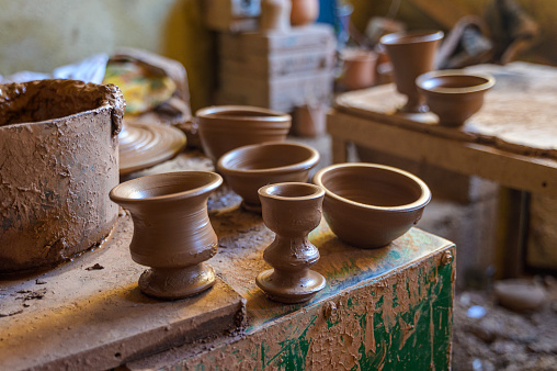 Clay pots placed on shabby table for drying in Moroccan pottery workshop against blurred background