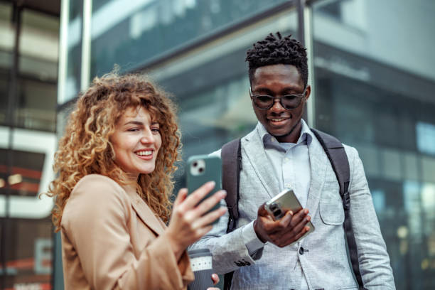 istock Two cheerful colleagues using smartphones outdoors 2145789797