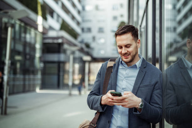 istock Well dressed handsome businessman using phone while standing in front of modern building at the city 2145790290