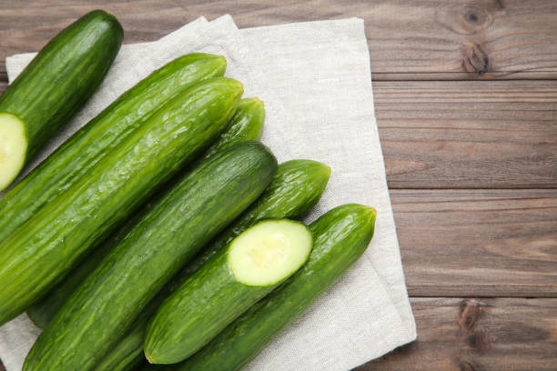 istock Fresh cucumbers with napkin on brown wooden background 2145822184