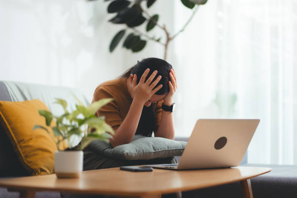istock Asian woman sitting at home using laptop, feels concerned thinking about work. 2145857211
