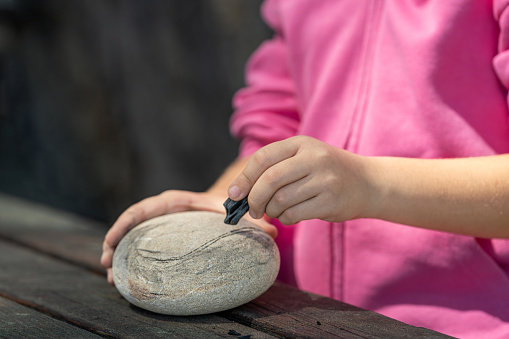 Girl drawing on a stone outdoors in the park